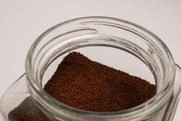 Transparent glass jar with ground coffee on a background, natural roasted ground coffee in a jar, a morning pick-me-up, caffeine for vigor, energy boost for the whole day, a tonic drink, a habit.