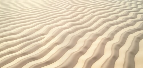 Fototapeta premium Close up view of textured surface of beach sand. Rippled patterns create mesmerizing design. Light beige sand highlights beauty of natural texture. Relaxing, tranquil scene. Image evokes summer