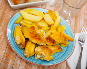 Crispy grilled chicken wings served with potato on plate