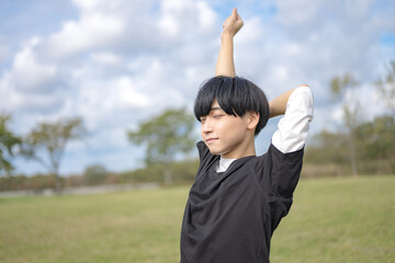 青空と体を伸ばす爽やかな男性