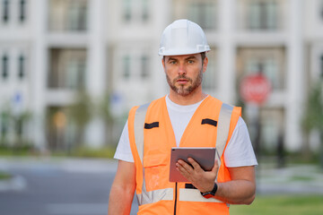 Fototapeta premium Engineer with tablet, building inspection. Builder at building site. Construction manager or engineer in helmet outdoor. Male construction engineer. Architect or engineer at a construction site.