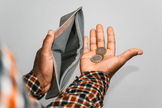 Black hands Holding empty opened men wallet With few Ghanaian cedi coins in palm. no money poor broke person concept