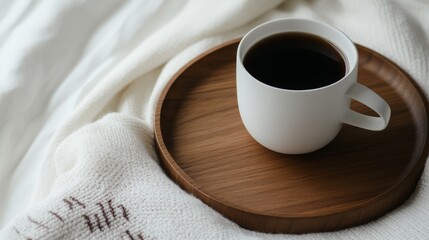 Obraz premium Cozy morning with a steaming cup of coffee on a wooden tray on a soft blanket