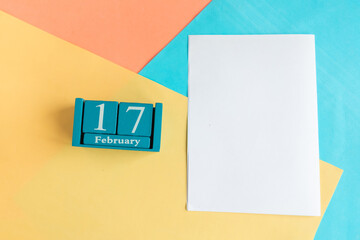 February 17. Blue cube calendar with month and date and white mockup blank on color geometric...