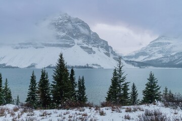 Snowy mountain lake scene under a cloudy sky. Winter landscape with snow-capped peaks and a serene lake. Nature's beauty in a cold, tranquil setting. , Banff National Park, Alberta, Canada