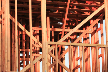 Framing structure of a wooden residential building under construction, showcasing vertical and diagonal beams, precise jointing, and natural lighting during the early stages of development
