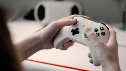 Modern technology and gaming influence development of children and teens, fostering skills and concentration. Close-up of gamer using controller and joystick highlights focus and interaction