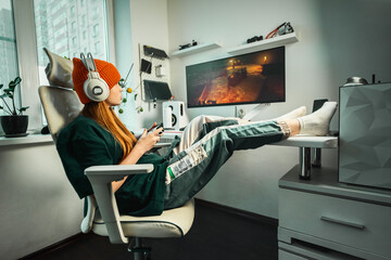 Girl enjoying video game in ergonomic chair with cutting-edge gaming equipment. Workplace features...