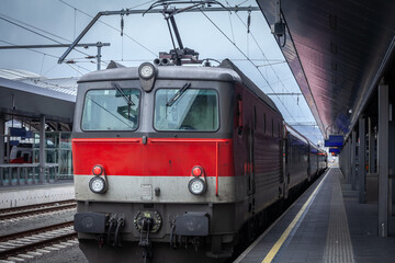 A red passenger train stands poised at Graz Hauptbahnhof, symbolizing Austria’s efficient rail...
