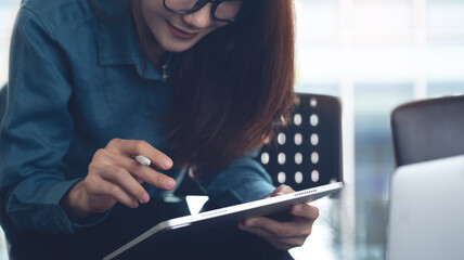 Business woman using digital tablet, reading and proofing business document, working at modern...