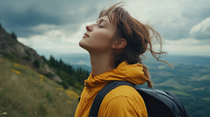 young woman in yellow jacket enjoys fresh mountain air, surrounded by nature. Her hair flows gently in breeze as she takes moment to appreciate beautiful landscape