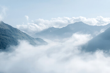 Majestic mountains shrouded in mist, creating serene and tranquil landscape. soft clouds envelop peaks, enhancing beauty of nature scenery