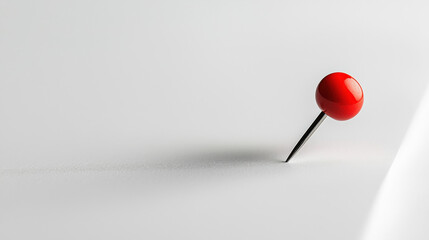 A red pushpin is stuck on a white paper