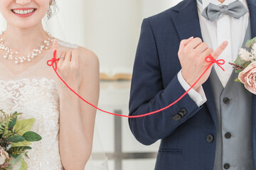 結婚式場で赤い糸で結ばれる新郎新婦（ブライダル・ウェディング）
