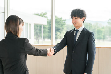 企業のオフィス・会議室で握手をして挨拶・自己紹介・契約を結ぶビジネスマン
