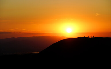 Golden Sunset Over Rolling Hills with Silhouetted Figures on the Horizon