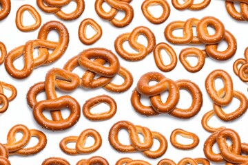Pattern of salted pretzels on a white background with a closeup view of crunchy and baked snacks, showcasing a delicious and tasty treat for breakfast or dessert