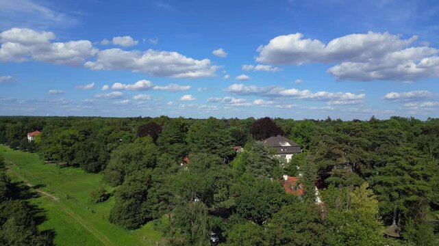 nikolassee, a residential district in berlin, featuring houses nestled within a dense forest, with the city skyline visible on the horizon. Stunning aerial view flight ascending drone