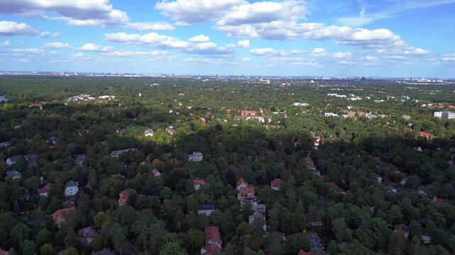 nikolassee, a residential district in berlin, featuring houses nestled within a dense forest, with the city skyline visible on the horizon. Fabulous aerial view flight speed ramp motion time lapse