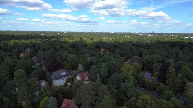 nikolassee, a residential district in berlin, featuring houses nestled within a dense forest, with the city skyline visible on the horizon. Beautiful aerial view flight panorama overview drone