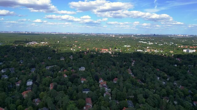 nikolassee, a residential district in berlin, featuring houses nestled within a dense forest, with the city skyline visible on the horizon. Marvelous aerial view flight static tripod hovering drone