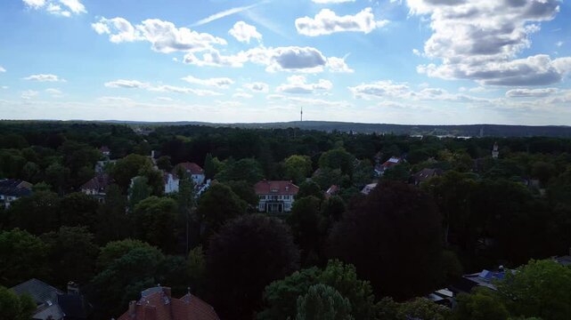nikolassee, a residential district in berlin, featuring houses nestled within a dense forest, with the city skyline visible on the horizon. Wonderful aerial view flight pull in drone