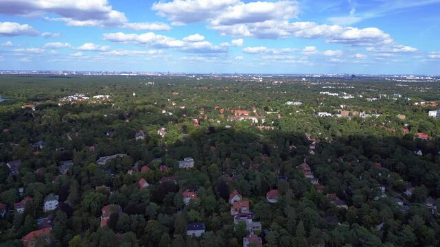 nikolassee, a residential district in berlin, featuring houses nestled within a dense forest, with the city skyline visible on the horizon. Spectacular aerial view flight overflight flyover drone