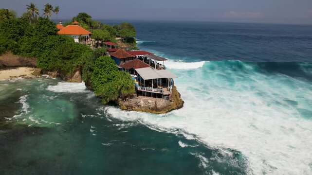4K drone video of huge waves crashing against the cliffs on Nusa Ceningan near Bali in Indonesia. There is a cafe at the top of the cliffs where people can watch the large wavs from.