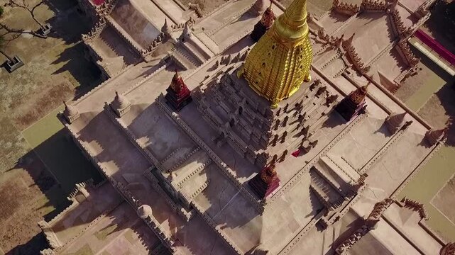 A stunning bird's-eye point of interest aerial shot of the White Temple at Ananda Temple, Bagan, Myanmar, highlighting the intricate architecture and the gleaming golden Sertok.