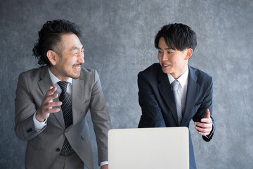 笑顔でパソコンを見るビジネスマン　上司と部下　上司に企画を提案する