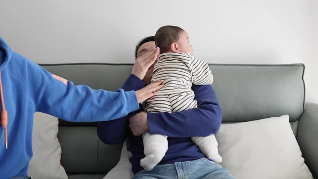 A 6 -month -old baby, Shanghai, China, and grandmother live. They have their baby burp on the sofa of the apartment living room.