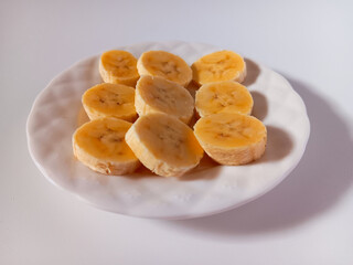 Sweet ripe banana slices on plate isolated on white background