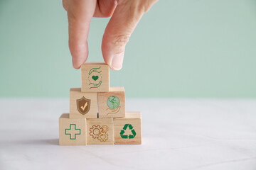 Hands holding wooden blocks with HSE and health, safety and environment icons, for preventing...