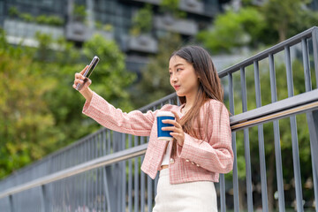 Portrait smiling beauty asian woman posing look at camera making live selfie, content, vlogger, blogger, live video streaming, broadcast, podcast, online influencer and creator on smartphone at city