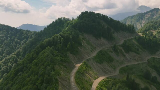 Drone view of lush green mountains with forest and unpaved roads on hill in Gebele, Azerbaijan