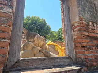 Image of the reclining Buddha through a wooden window frame