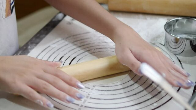 Hands using circular cutter to shape gyoza dough into perfect wrappers on a floured surface, with a rolling pin and baking tools nearby, showcasing the meticulous process of making Japanese dumplings