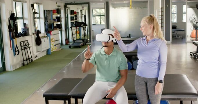 Using VR headset, man in rehab guided by therapist in rehabilitation center