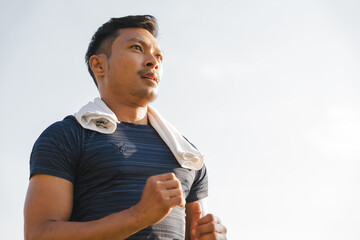 A male athlete enjoys a morning run in the park, smiling and exercising outdoors. Embracing fitness...