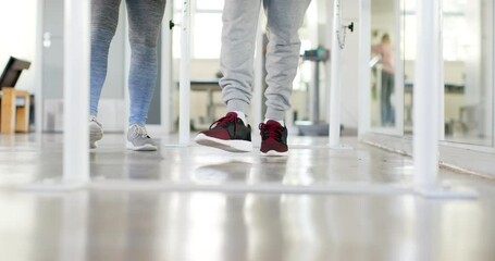Walking on parallel bars, person in rehabilitation with therapist in gym