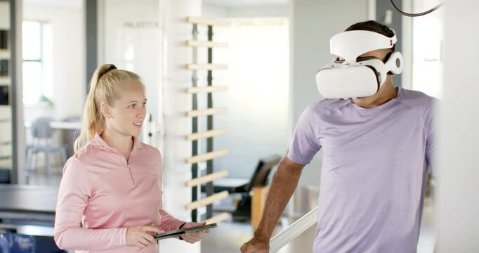 Using VR headset, man in disability rehab with therapist holding tablet