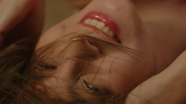 beautiful macro of an attractive joyful woman smiling and sensually playing with her hair in slow motion
