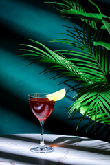 Irish Jack Rose alcoholic cocktail drink with Irish whiskey, calvados, lime juice, grenadine and lime wedge. Green background, hard light and shadows