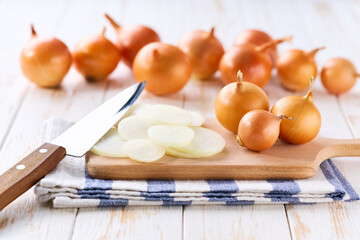 Sliced yellow onions in a cutting board on a light kitchen table.