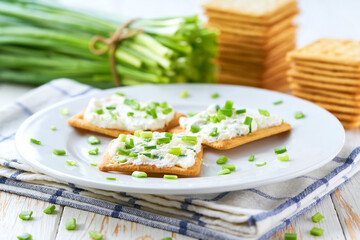 Healthy breakfast concept, biscuits with a cream cheese spread and freshly cut chives on a wooden...