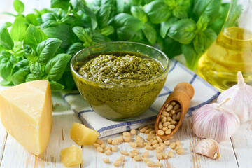 Bowl of tasty pesto sauce with basil leaves on a white table.