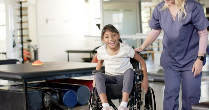 In rehabilitation center, therapist assisting girl with cerebral palsy in wheelchair during therapy