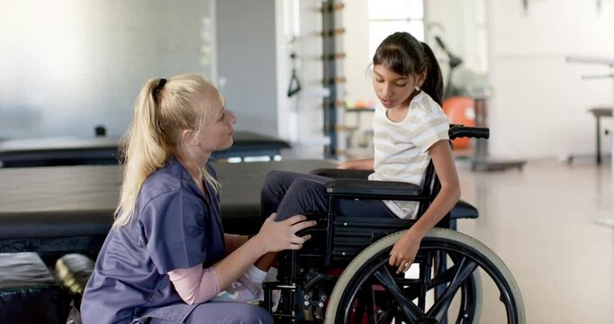 Rehabilitation therapist assisting girl with cerebral palsy in wheelchair during therapy session