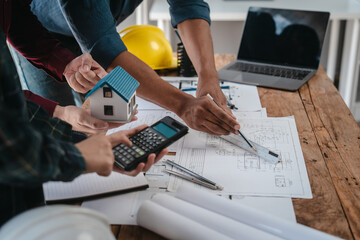 Two male engineers and a strong woman discuss blueprints and home design at a table. They work as a professional team, collaborating on construction projects with precision and expertise