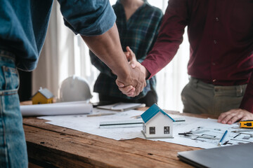 Two male engineers and a strong woman discuss blueprints and home design at a table. They work as a professional team, collaborating on construction projects with precision and expertise